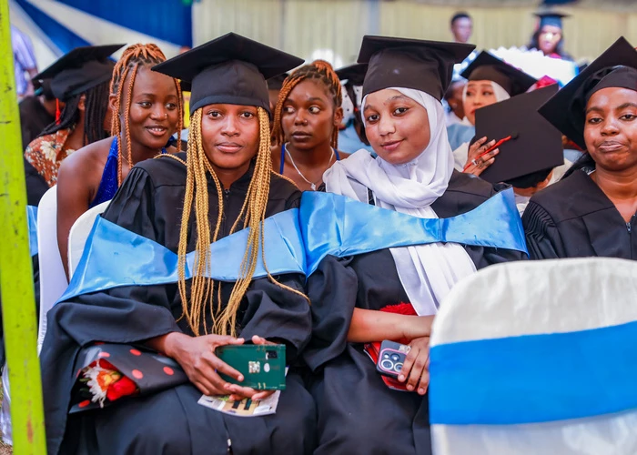 A student in graduation attire speaking at a podium during a ceremony